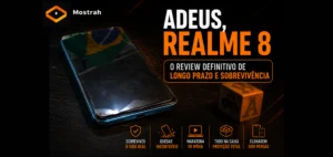 Um smartphone com sinais de uso intenso e a tela levemente descolada descansando sobre uma mesa escura de trabalho, com um pequeno brinquedo infantil ao fundo.